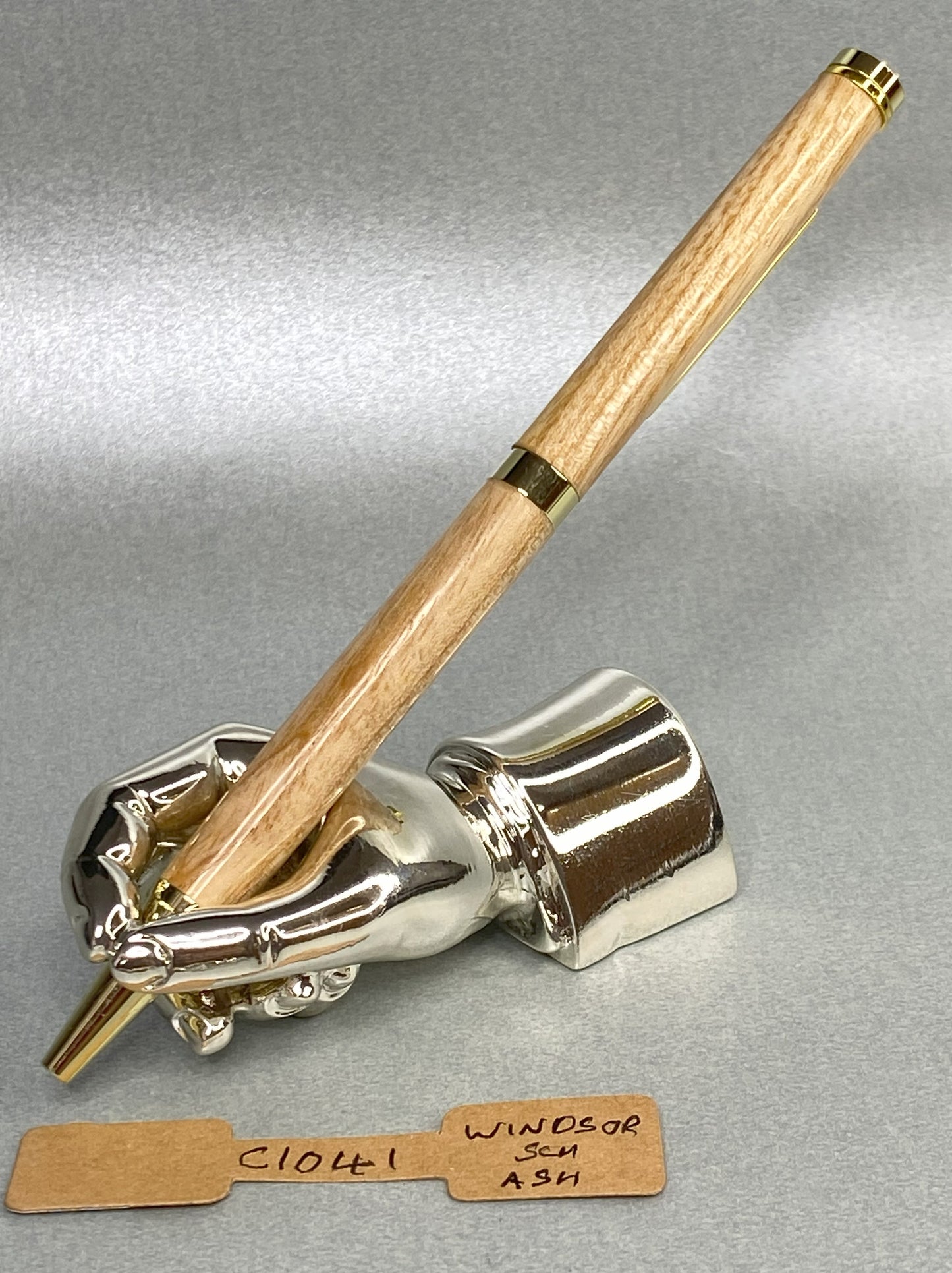 Ash wood with gold plated fittings and a cricket bat clip on a chrome plated stand in the shape of a hand