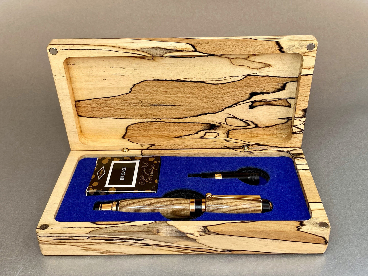 Spalted Beech wood hand crafted presentation box with its lid open showing one hand turned hand crafted pen made from Black Ash Wood, It has Gold Plated fittings and black accents on the nib, there is a second nib in the box that is a rollerball type so you can switch between the two.