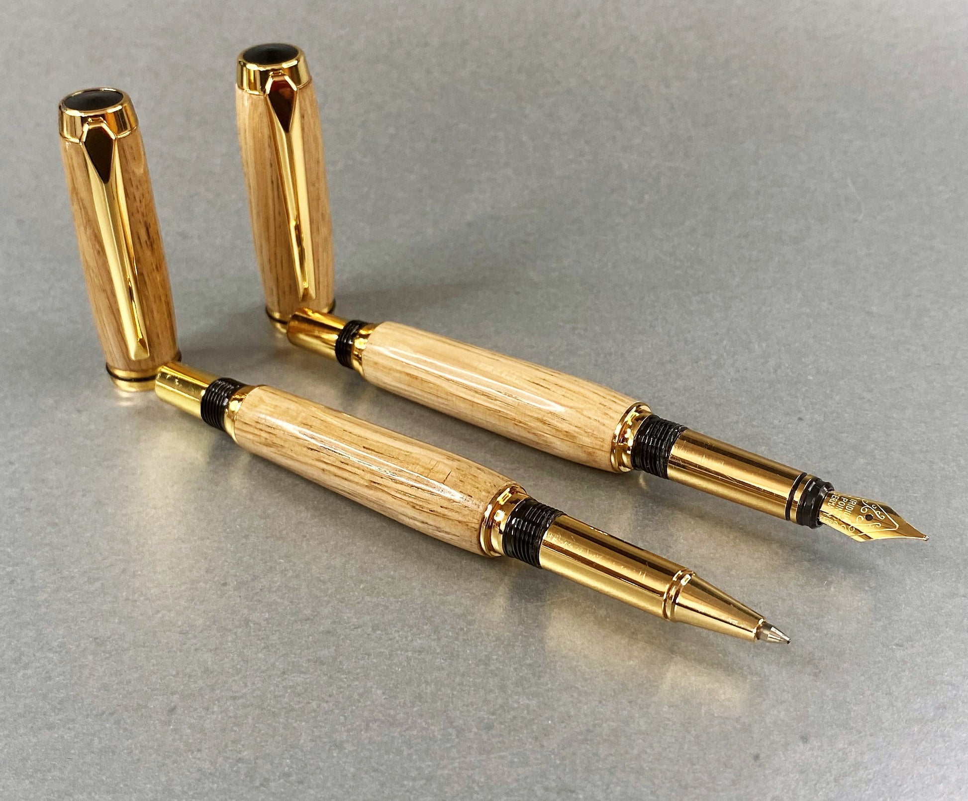 Two hand crafted and turned pens made from French Oak and has Gold Plated fittings, one is a fountain pen and the other is a Rollerball pen