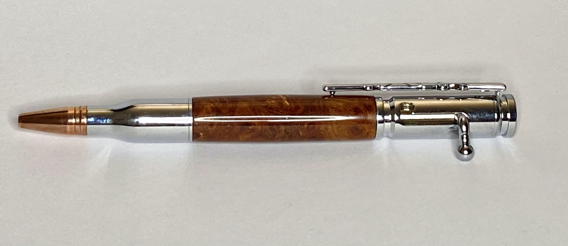 A handturned Popular Burr wood Bolt action pen with Chrome plated fittings and copper coloured tip to give the "bullet" effect