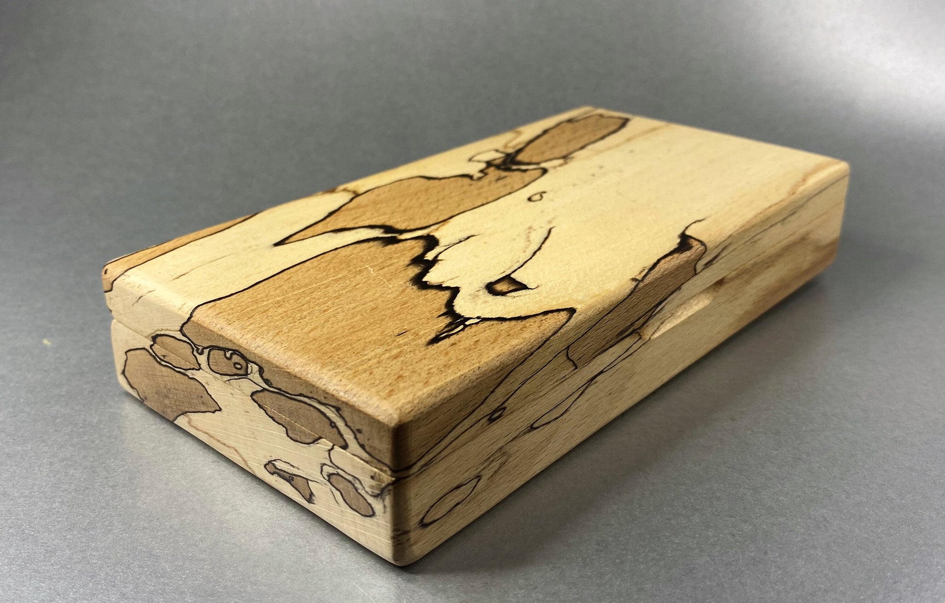 Spalted Beech wood hand crafted presentation box with its lid closed showing the figuring and grain effect on the end grain and on the lid as well.