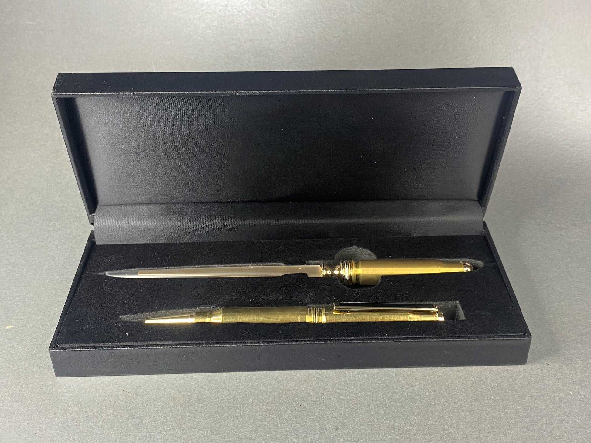 Open lidded black card box with a pen and a letter opener made from once fired .308 brass shell cases