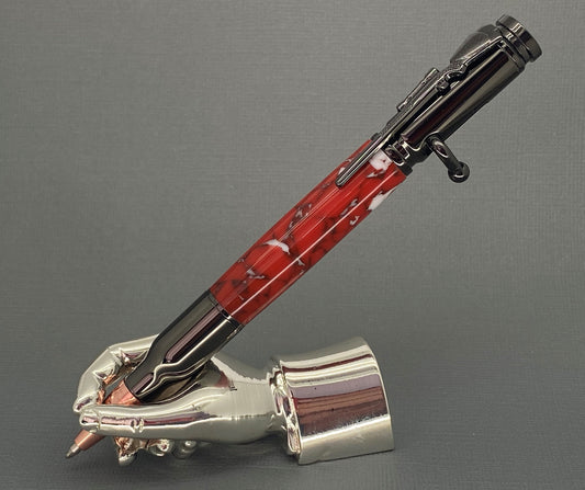 A right hand shaped metal base holding a handturned Red & White acrylic Bolt action pen as you would hold it to write with.