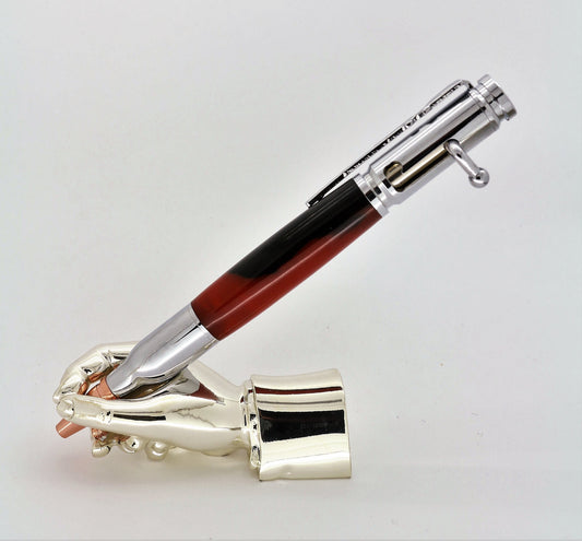 A right hand shaped metal base holding a handturned Black & Red Polyester acrylic Bolt action pen as you would hold it to write with.