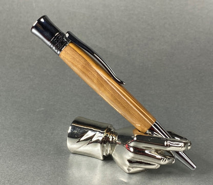 A right hand shaped metal base holding a handturned Olive Wood pen as you would hold it to write with.